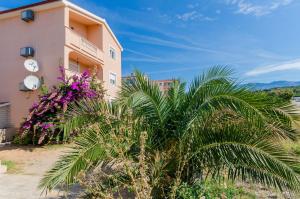 een roze gebouw met palmbomen ervoor bij Apartments Jasmin in Barbat na Rabu