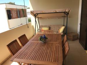 a wooden table with chairs and a bed on a balcony at La maison de Medea in Pulsano