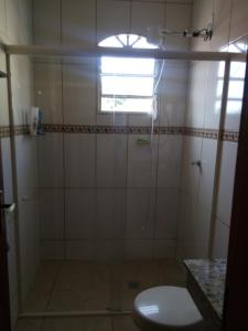 a bathroom with a shower with a toilet and a window at Pousada do Sonho in Cunha