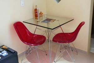 a glass table with two red chairs and a bottle of wine at Rhodes Motel Recife in Recife