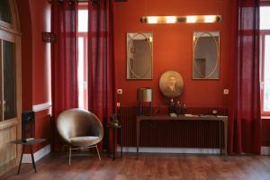 a room with red walls and a chair and mirrors at Hotel Des Arts in Wimereux