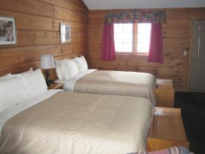 two beds in a room with wooden walls and a window at Sunset Inn in North Bay