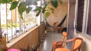a porch with a hammock and two chairs and windows at Hostal Rich in Medellín