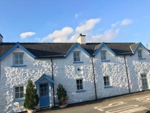 a white house with a blue door on a street at Pen Y Bont Cottage Llanuwchllyn Bala in Llanuwchllyn