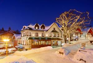 a large house is covered in snow at night at Hotel pizzeria Belmonte in Špindlerův Mlýn
