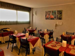 a dining room with tables and chairs with red tablecloths at Green Hotel in Poviglio