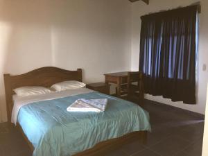 a bedroom with a bed and a table and a window at Cabinas Lindo Horizonte in San Pedro