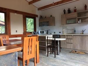 a kitchen with wooden cabinets and a table and chairs at Cabañas JL in Las Trancas