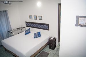 Un dormitorio con una cama blanca con almohadas azules. en Vacation Rental - Upper Floor Room at Casa Cocoa, en Cozumel