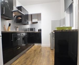 a kitchen with black cabinets and a wooden floor at Walthall Place by SG Property Group in Crewe