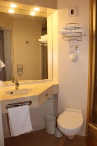 a bathroom with a sink and a toilet and a mirror at Brit Hotel Les Evens in Saint-Saturnin