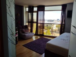 a bedroom with a bed and a chair and a large window at LxRiverside Suite Apartment in Lisbon