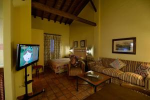 uma sala de estar com um sofá e uma televisão em Alojamientos Turísticos Rurales La Barataria em Titulcia