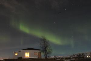 een afbeelding van het noorderlicht in de lucht boven een huis bij Gamla Húsið - The Old House in Selfoss