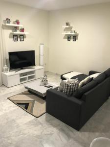 sala de estar con sofá negro y TV en Estepona valle romano, en Estepona