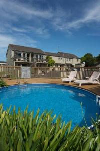 a large blue swimming pool with two chairs and a house at Howick Motor Lodge in Auckland