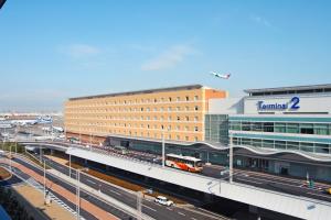 a train is parked at a train station next to a building at Haneda Excel Hotel Tokyu Haneda Airport Terminal 2 in Tokyo