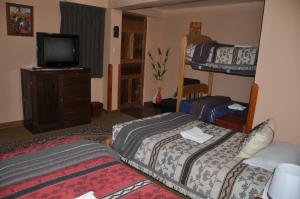 a bedroom with two beds and a tv and a bunk bed at Hostal Goya Andina in Cusco