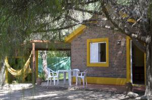 a house with a table and chairs on the porch at Complejo de Cabañas Pach - Flo in San Marcos Sierras