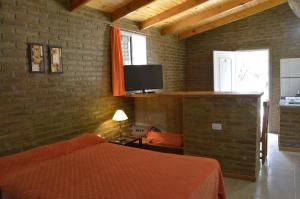a bedroom with a bed and a tv on a brick wall at Complejo de Cabañas Pach - Flo in San Marcos Sierras