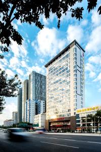 a tall white building in front of a city at Guangzhou Jin Wan Li Business Hotel in Guangzhou