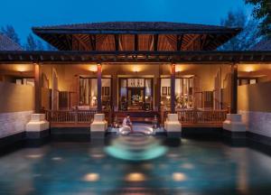 a person sitting in a swimming pool in front of a house at Four Seasons Resort Langkawi in Tanjung Rhu