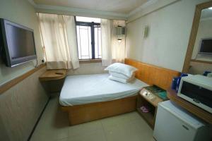 um pequeno quarto com uma cama e uma televisão em Astronaut's Hotel em Hong Kong