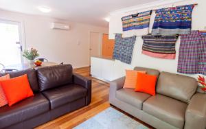 a living room with two leather couches and orange pillows at One of a Kind Apartments in Canberra
