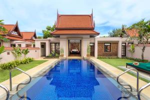 a villa with a swimming pool in front of a house at Banyan Tree Phuket in Bang Tao Beach