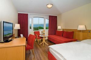 a hotel room with a bed and a desk and a tv at Restaurant-Hotel Seeblick in Mörigen