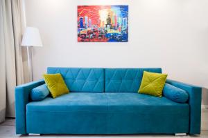 a blue couch with two yellow pillows in a room at Hosapartments City Center in Warsaw