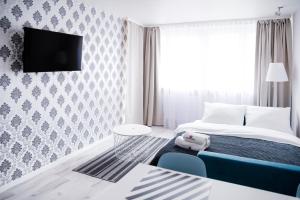 a bedroom with a bed and a tv on a wall at Hosapartments City Center in Warsaw