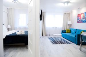 a room with a bed and a blue couch at Hosapartments City Center in Warsaw