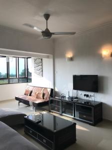 uma sala de estar com um sofá e uma televisão de ecrã plano em Sri Sayang Apartment at Batu Ferringhi em Batu Ferringhi