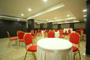 a conference room with a white table and red chairs at Central Beacon Hotel in Surat