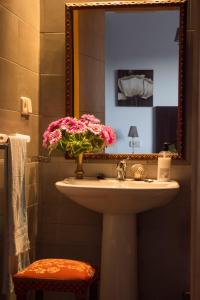 a bathroom with a sink with a vase of pink flowers at Villa Rosa Amparo in Córdoba