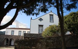 a white house with a stone wall and trees at Quinta Atlantis in Povoação