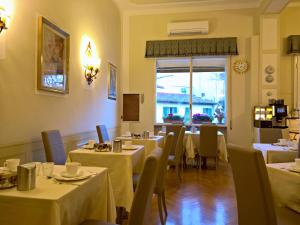 un ristorante con tavoli e sedie bianchi e una finestra di Hotel David a Firenze