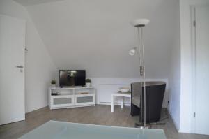 uma sala de estar branca com uma televisão e uma mesa em Ferienwohnung Tiberquelle em Dülmen