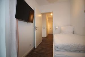 a small bedroom with a bed and a television on the wall at Wohnen am Yachthafen W48 in Cuxhaven