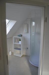 uma casa de banho branca com um chuveiro e um frigorífico em Ferienwohnung Tiberquelle em Dülmen