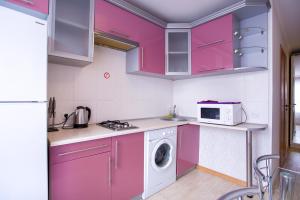 ムィコラーイウにあるЗатишна квартира у самому центрі , на Соборнійのピンクのキャビネットと洗濯機付きのキッチンが備わります。
