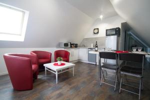 a living room with red chairs and a table and a kitchen at ENTRE LOIRE ET CHER Gîte "Le Nid Douillet" in Tour-en-Sologne