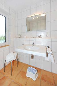 La salle de bains est pourvue d'un lavabo, d'une chaise et d'un miroir. dans l'établissement Nordseegartenpark Terrassien, à Bensersiel
