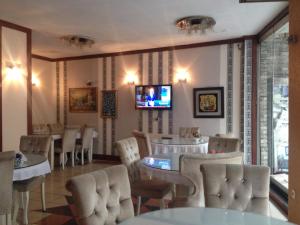 un restaurant avec des tables et des chaises ainsi qu'une télévision murale. dans l'établissement Turvan Hotel, à Istanbul