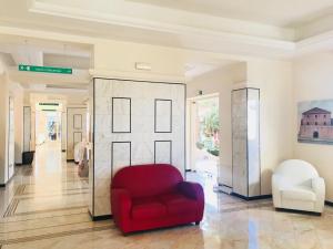 a living room with a red chair and a glass door at Hotel Terme Marine Leopoldo II TERME & SPA in Marina di Grosseto
