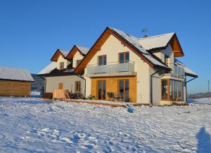 a house in the snow in front at Pokoje na Wzgórzu in Kasina Wielka