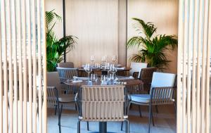 a dining room with tables and chairs and palm trees at Hotel Arima & Spa - Small Luxury Hotels in Donostia-San Sebastián