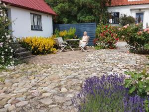 a woman sitting on a bench in a garden at Peterslund in Östra Tommarp +4 photos