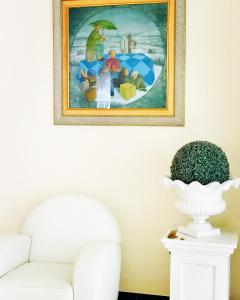 a painting hanging on a wall above a white couch at Hotel Terme Marine Leopoldo II TERME & SPA in Marina di Grosseto